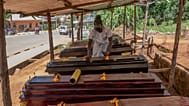 Djakisa Christian, 18, a funeral home manager, dusts coffins for sale at his shop in Bunia, Congo.
