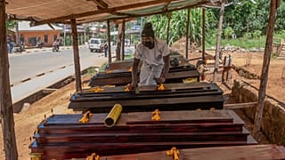 Djakisa Christian, 18, a funeral home manager, dusts coffins for sale at his shop in Bunia, Congo.