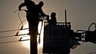 Employees of the national electricity distributor work in freezing temperatures to fix power lines damaged by blizzards, near Pitulicea, Romania, Wednesday, Feb. 15, 2012.