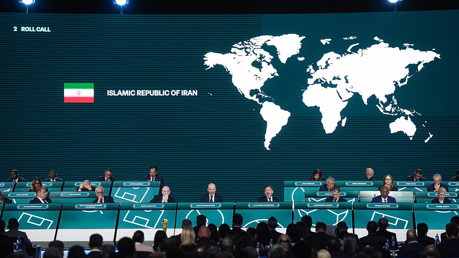 تم تسجيل غياب إيران بينما يقوم الأمين العام للفيفا ماتياس غرافستروم، الرابع من الأمام إلى اليسار، بإجراء عملية التحقق من الأسماء خلال مؤتمر الفيفا السادس والسبعين في فانكوفر، 
