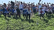 Participantes compiten en la carrera masculina cuesta abajo del tradicional concurso anual de rodar queso en Cooper's Hill, en Brockworth