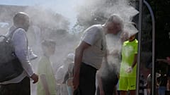 Des spectateurs se rafraîchissent avec l’eau des arroseurs lors d’une journée chaude à Roland-Garros.