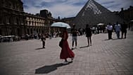 FILE- A woman holds her umbrella to protect from the sun at the Louvre Museum as the temperature rose up to 31 degrees Celsius  in Paris on Friday, June 20, 2025