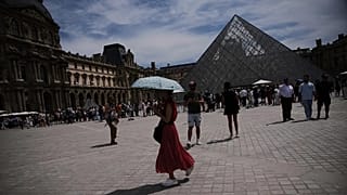 FILE- A woman holds her umbrella to protect from the sun at the Louvre Museum as the temperature rose up to 31 degrees Celsius  in Paris on Friday, June 20, 2025