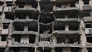 Семья сидит на балконе сильно повреждённого жилого дома в южных пригородах Бейрута, 25 апреля 2026 года