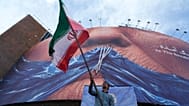 رجل يلوّح بالعلم الإيراني في وسط طهران، 6 مايو/ أيار 2026.