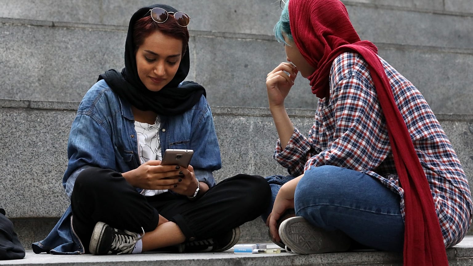 في هذه الصورة الملتقطة يوم الثلاثاء 2 يوليو/تموز 2019، تعمل امرأة إيرانية على هاتفها المحمول أثناء قضاء فترة ما بعد الظهر على درجات خارج مركز للتسوق في شمال طهران، إيران. 
