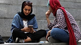 في هذه الصورة الملتقطة يوم الثلاثاء 2 يوليو/تموز 2019، تعمل امرأة إيرانية على هاتفها المحمول أثناء قضاء فترة ما بعد الظهر على درجات خارج مركز للتسوق في شمال طهران، إيران. 