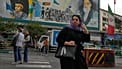 امرأة تعبر الشارع أمام لوحة لمؤسس الثورة الإيرانية الراحل آية الله الخميني وقوات الباسيج شبه العسكرية في وسط مدينة طهران، إيران، الأحد 24 مايو 2026. 