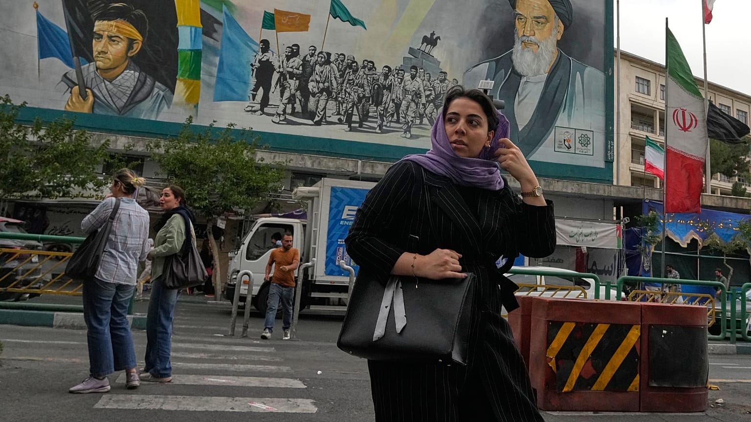 امرأة تعبر الشارع أمام لوحة لمؤسس الثورة الإيرانية الراحل آية الله الخميني وقوات الباسيج شبه العسكرية في وسط مدينة طهران، إيران، الأحد 24 مايو 2026. 