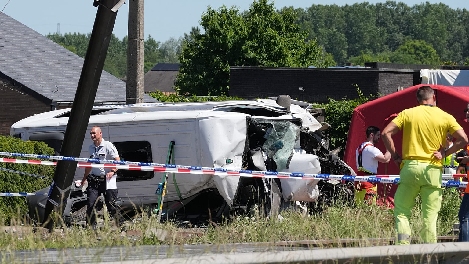 Emergency personnel work at a level crossing where a train collided with a school van in Buggenhout, Belgium, Tuesday, 26 May, 2026. (AP Photo/Marius Burgelman)