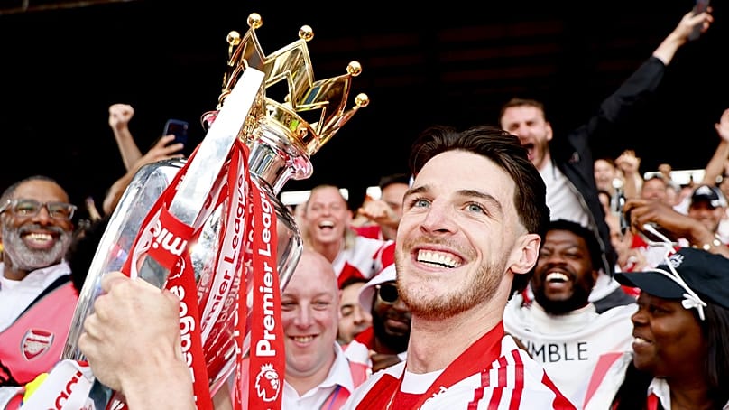 Declan Rice, az Arsenal játékosa az angol bajnokság megnyerésért járó trófeával csapattársai között Londonban 2026. május 24-én 
