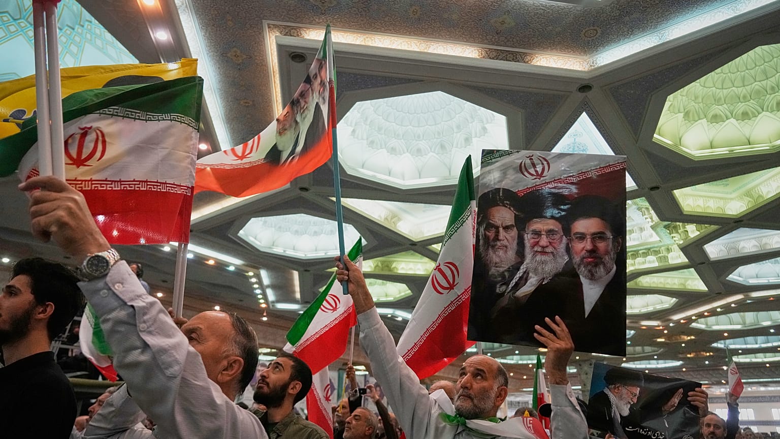 رجل يحمل لافتة تضم صور قادة إيرانيين خلال مراسم في طهران، الأحد 24 مايو/أيار 2026.
