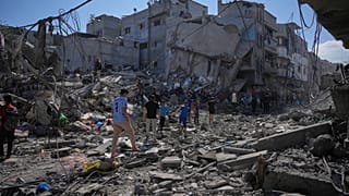 Palestinianos inspecionam os escombros de um edifício destruído por um ataque aéreo israelita em Nuseirat, no centro da Faixa de Gaza, terça-feira, 26 de maio de 2026.