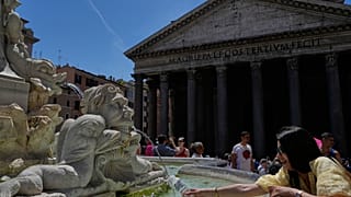 Uma mulher enche uma garrafa de água junto ao Panteão, no centro de Roma, numa terça-feira, 26 de maio de 2026, quando se preveem 32 graus Celsius (89,6 F). (AP Photo)