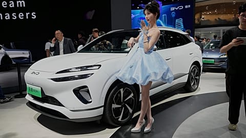 File - A model poses near the Sea Lion 06 DM-i model from BYD at the Shanghai auto show on Wednesday, 23 April 2025.