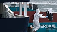 People in protective gear remove waste from the MV Hondius cruise ship after its arrival at the Port of Rotterdam, Netherlands, Monday, May 18, 2026.