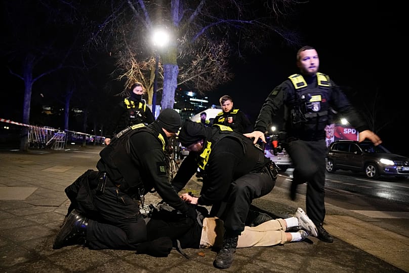 عناصر من الشرطة الألمانية يوقفون رجلاً عند نصب الهولوكوست التذكاري في برلين، بعد إصابة شخص آخر بجروح خطرة، في 21 فبراير/ شباط 2025.