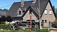 Um veículo jaz de lado junto a uma casa após uma colisão entre um comboio e uma carrinha numa passagem de nível em Buggenhout, Bélgica, terça-feira, 26 de maio de 2026.