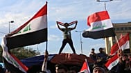  يلوح أتباع رجل الدين الشيعي مقتدى الصدر بالأعلام الوطنية أثناء إنهاء اعتصامهم خارج المنطقة الخضراء شديدة الحراسة في بغداد بالعراق