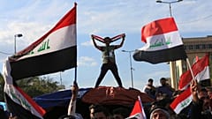  يلوح أتباع رجل الدين الشيعي مقتدى الصدر بالأعلام الوطنية أثناء إنهاء اعتصامهم خارج المنطقة الخضراء شديدة الحراسة في بغداد بالعراق