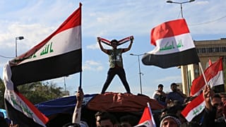  يلوح أتباع رجل الدين الشيعي مقتدى الصدر بالأعلام الوطنية أثناء إنهاء اعتصامهم خارج المنطقة الخضراء شديدة الحراسة في بغداد بالعراق