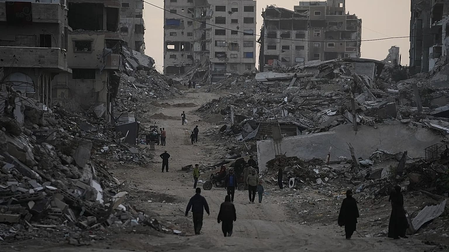 Palestinians walk through the destruction in the Al-Karama neighbourhood of Gaza City, 30 November, 2025