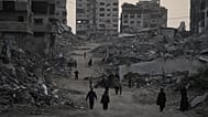 Palestinians walk through the destruction in the Al-Karama neighbourhood of Gaza City, 30 November, 2025