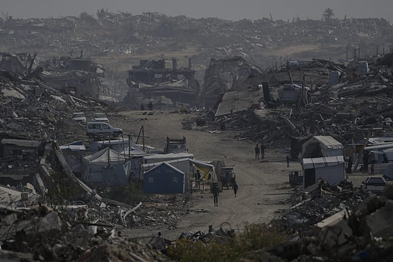 Palestinians walk through the destruction left by the Israeli air and ground offensive in Gaza City, 5 December, 2025