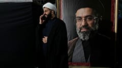 رجل دين يتحدث عبر هاتفه المحمول بجوار صورة المرشد الأعلى الإيراني مجتبى خامنئي خلال تجمع مؤيد للحكومة طهران، إيران، يوم الاثنين 18 مايو/أيار 2026.