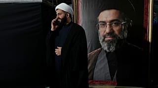 رجل دين يتحدث عبر هاتفه المحمول بجوار صورة المرشد الأعلى الإيراني مجتبى خامنئي خلال تجمع مؤيد للحكومة طهران، إيران، يوم الاثنين 18 مايو/أيار 2026.
