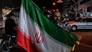 رجل يحمل العلم الإيراني في حملة مؤيدة للحكومة في وسط مدينة طهران، إيران، الجمعة 8 مايو 2026. (AP Photo/فاهد سليمي)