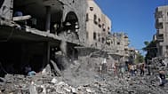 فلسطينيون يتفقدون أنقاض مبنى دمر في غارة جوية إسرائيلية في النصيرات بوسط قطاع غزة، الثلاثاء 26 مايو 2026. (AP Photo/عبد الكريم حنا)