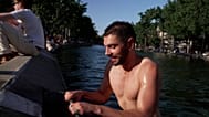 A swimmer climbs out onto the bank of the Canal Saint‑Martin after jumping in.