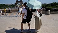 يلتقط السياح تحت المظلة صورًا من نوعهم في ساحة تروكاديرو بجوار برج إيفل، الثلاثاء 26 مايو 2026، خلال يوم مشمس في باريس. (AP Photo/ميشيل أويلر)