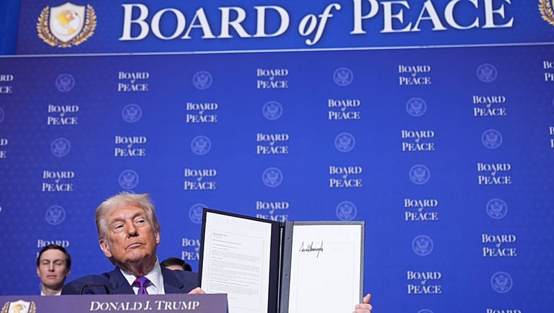 US President Donald Trump holds up a signed resolution during a Board of Peace meeting in Washington, 19 February, 2026