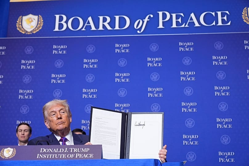 US President Donald Trump holds up a signed resolution during a Board of Peace meeting in Washington, 19 February, 2026