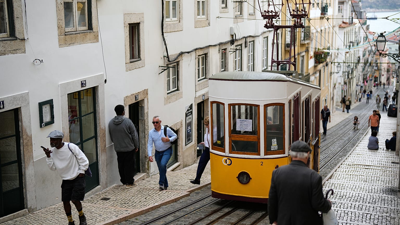 ARQUIVO - Pessoas passam junto ao funicular da Bica, estacionado em Lisboa