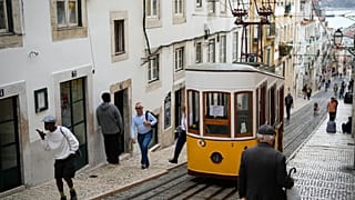 ARQUIVO - Pessoas passam junto ao funicular da Bica, estacionado em Lisboa