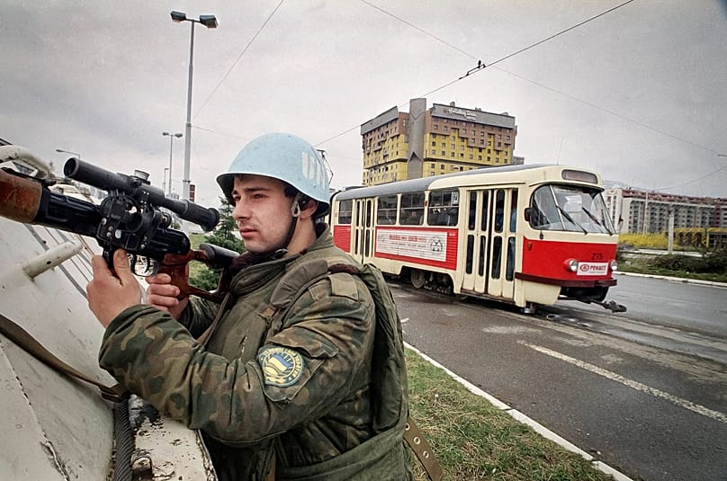 Un casco blu protegge nel '94 la circolazione in Ulica Zmaja od Bosne, conosciuta ormai come Sniper Alley per via del pericolo di cecchini: sullo sfondo l'hotel Holiday Inn
