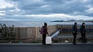 Un hombre lleva sus pertenencias junto a agentes de policía tras ser desalojado de un campamento que se incendió en Níjar, Almería, el lunes 30 de enero de 2023