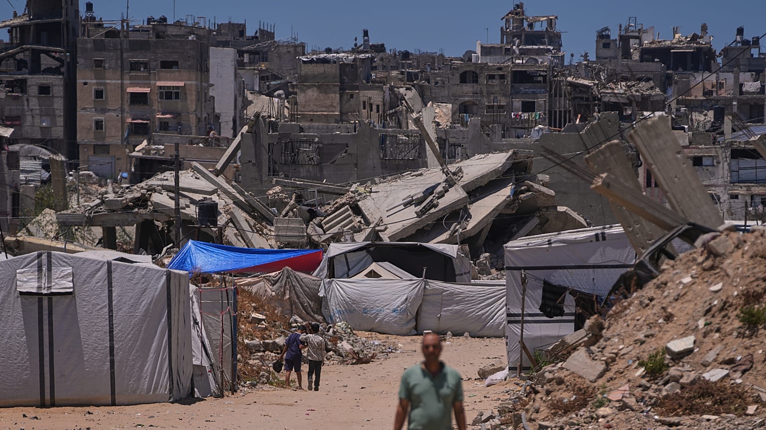 فلسطينيون يسيرون على طول شارع محاط بالمباني التي دمرتها الغارات العسكرية الإسرائيلية خلال الحرب بين إسرائيل وحماس في خان يونس، جنوب قطاع غزة، الجمعة 29 مايو 2026. 