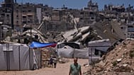 فلسطينيون يسيرون على طول شارع محاط بالمباني التي دمرتها الغارات العسكرية الإسرائيلية خلال الحرب بين إسرائيل وحماس في خان يونس، جنوب قطاع غزة، الجمعة 29 مايو 2026. 