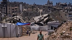 فلسطينيون يسيرون على طول شارع محاط بالمباني التي دمرتها الغارات العسكرية الإسرائيلية خلال الحرب بين إسرائيل وحماس في خان يونس، جنوب قطاع غزة، الجمعة 29 مايو 2026. 