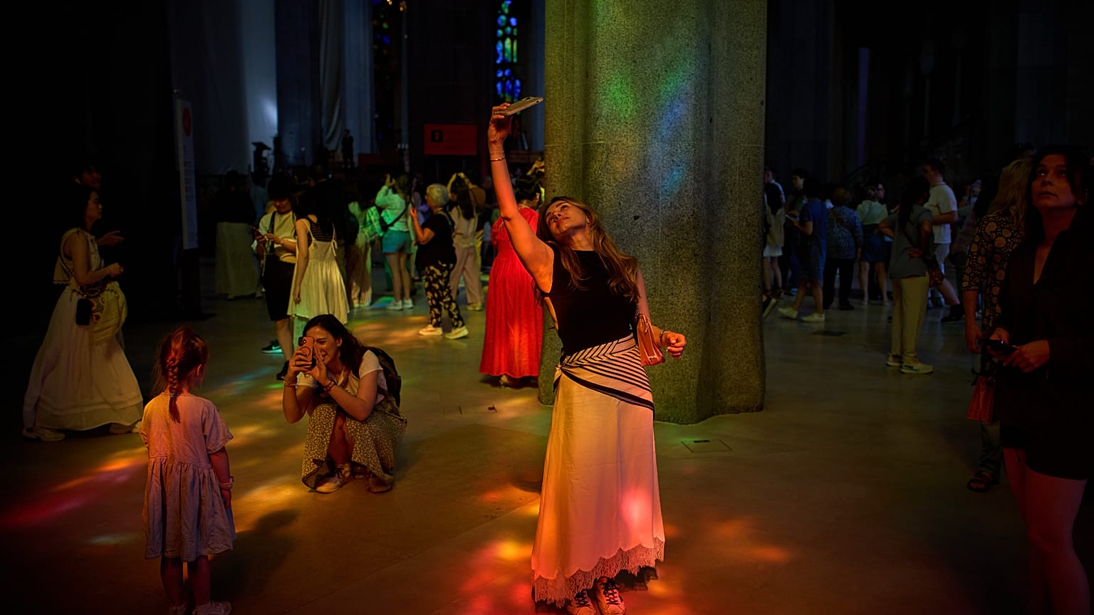 Una turista hace fotos dentro de la Sagrada Familia mientras la luz de sus vidrieras ilumina el interior, el martes 26 de mayo de 2026 en Barcelona