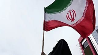 امرأة ترفع العلم الإيراني خلال حملة مؤيدة للحكومة في وسط العاصمة طهران، في 25 أبريل 2026.