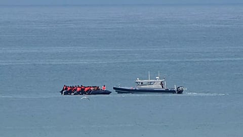 A boat thought to carry migrants is escorted by a vessel from the French Gendarmerie Nationale in the English Channel off Wimereux beach, 4 September, 2024