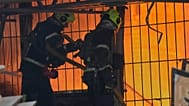Strażacy pracują na miejscu płonącego budynku po rosyjskim ataku rakietowym na Kijów.