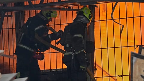 Tűzoltók dolgoznak égő épületnél orosz rakétatámadás után Kijevben