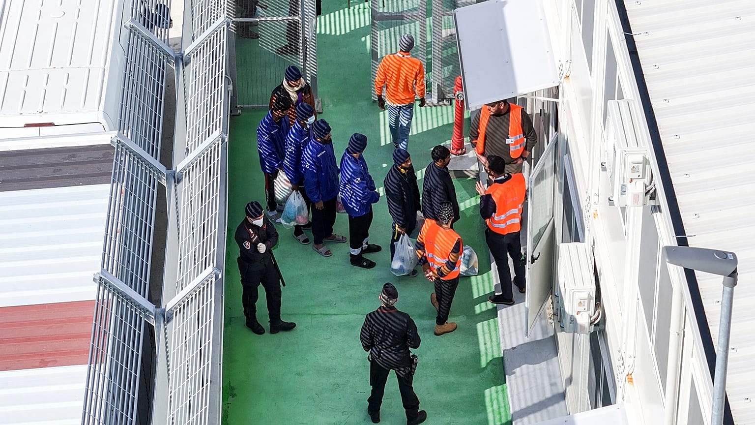 An aerial photograph taken by a drone shows migrants entering a detention center for processing following earlier court rejections, in the port of Shengjin